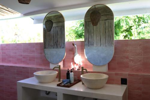 two sinks in a bathroom with two mirrors at Villa Norte in Gili Islands