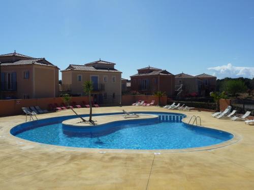 - une piscine dans une cour avec des chaises et des bâtiments dans l'établissement Villa Pays d'Oc, à Béziers