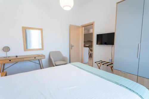a bedroom with a bed and a desk and a television at Vrachati Blue in Vrachati