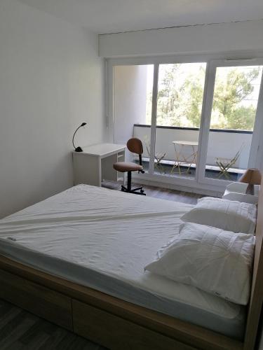 a bedroom with a large bed and a desk and window at Chambre dans colocation à Lormont proche Bordeaux in Lormont