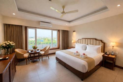 a hotel room with a bed and a desk and a window at Park Selections in Bhubaneshwar
