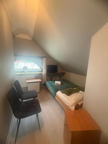 a attic bedroom with a bed and a chair at Korab Wisełka & SPA in Wisełka
