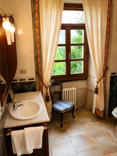 a bathroom with a sink and a window and a chair at Hotel Pazo Do Souto in Carballo