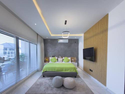 a bedroom with a green bed and a large window at Luxury Villa at THE HIDDEN DOMUS I Trassaco, East Legon in Accra