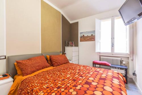 a bedroom with a bed with orange pillows and a tv at De' Fusari, Bologna by Short Holidays in Bologna