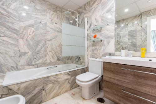 a bathroom with a white toilet and a tub and a sink at Doña Sofía in Fuengirola