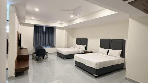 a bedroom with two beds and a television in it at Chhapaak Resort in Patna