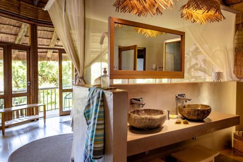 a bathroom with two sinks and a mirror at Thonga Beach Lodge in Mabibi