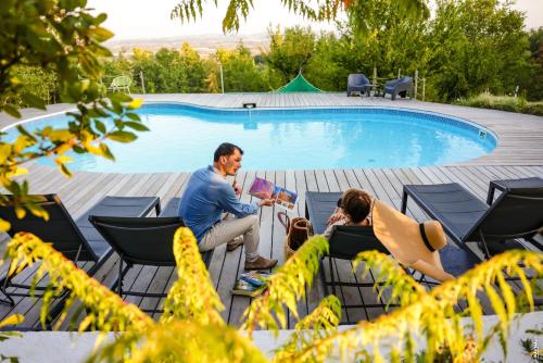 a group of people sitting by a swimming pool at Les Hauts de Jeanvert - Le Cèdre - Piscine - Gaillac in Gaillac
