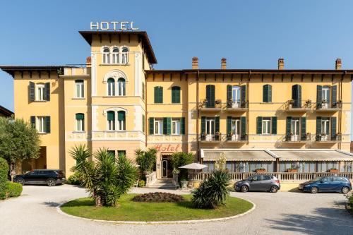 a large yellow building with cars parked in a parking lot at Hotel Maderno by Double Hospitality in Toscolano Maderno