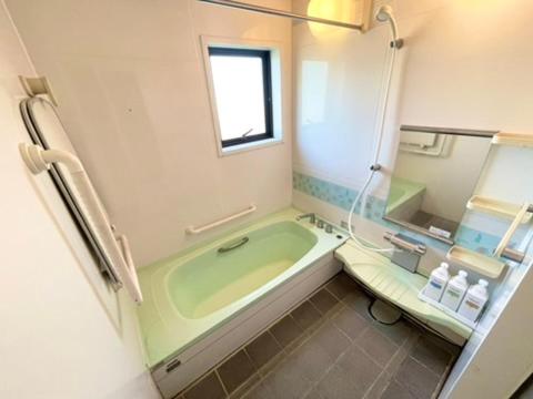 a bathroom with a green tub and a toilet at あざみ庵 屋久島 in Yakushima