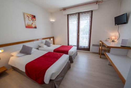 ein Hotelzimmer mit 2 Betten, einem Schreibtisch und einem TV in der Unterkunft Logis Hôtels - Hôtel et Restaurant Les Cordeliers in Casteljaloux