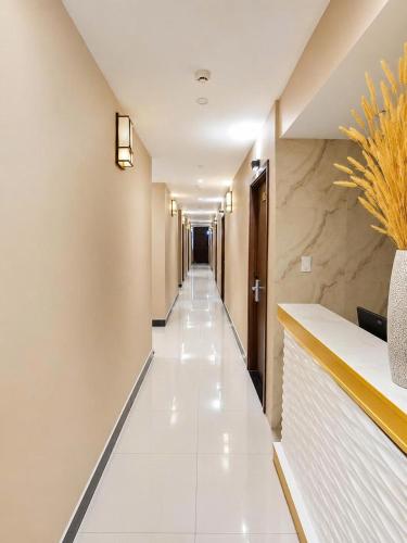 a corridor of a hotel with white tile floors and a long hallway at Bis Hotel Hồ Chí Minh in Chợ Phước Hải