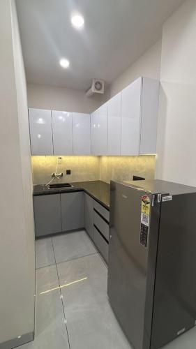 a kitchen with white cabinets and a refrigerator at Hotel Venezia Grand in Gurgaon