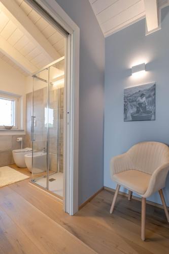 a bathroom with a glass shower and a chair at Villa Sarmassa in Narzole