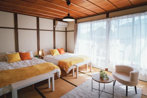 a bedroom with two beds and a chair at Nagoya kiyosu温もりの宿貸切一軒家駅近3分 in Nishi-biwajima