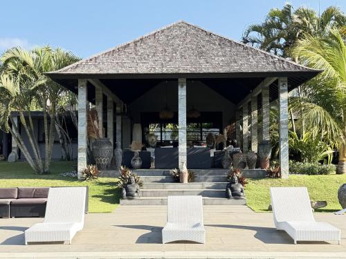 a pavilion with white chairs and a couch and palm trees at Life is One in Uluwatu