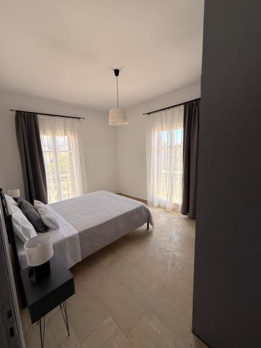 a white bedroom with a bed and two windows at Methoni Joanna House in Methoni
