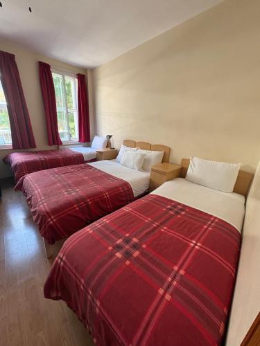three beds in a room with red and white sheets at Seven Dials Hotel Annexe in London