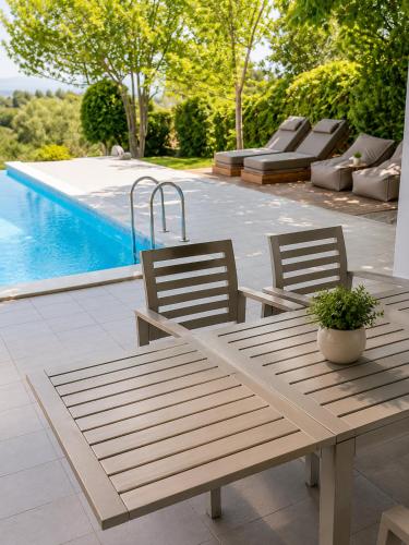 two chairs and a wooden table next to a pool at Villa Magnifica - Private Pool, Elevator & Sea View in Paliouri