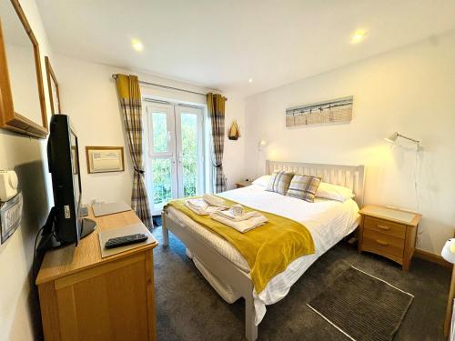 a bedroom with a bed and a desk with a television at Apartment 19 in Downderry
