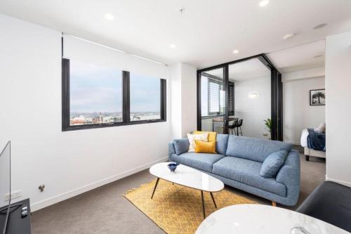 a living room with a blue couch and some windows at Sunset on the Esplanade in Newcastle