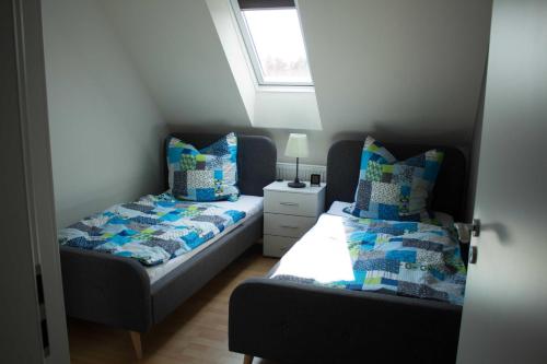 a bedroom with two beds and a window at Ferienhaus Moorspatz, 95143 in Rhauderfehn
