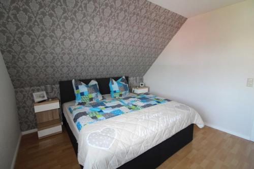 a bedroom with a bed in a room with a wall at Ferienhaus Moorspatz, 95143 in Rhauderfehn