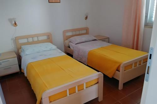 two beds in a small room with yellow sheets at Casa al Mare Ingresso Indipendente in Casalbordino