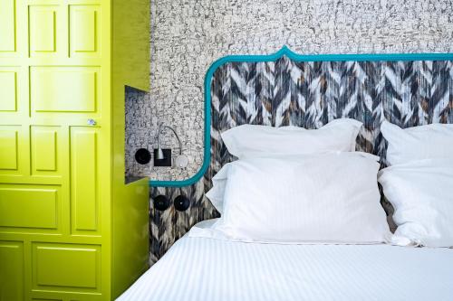 a bedroom with a bed with a blue headboard and white pillows at Hôtel Crayon Rouge - Louvre Palais Royal in Paris