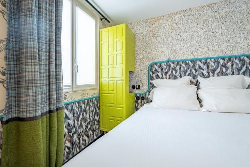a bedroom with a bed and a yellow door at Hôtel Crayon Rouge - Louvre Palais Royal in Paris