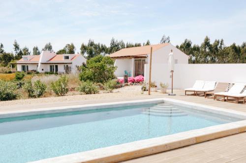 a swimming pool in front of a house at Vale das Estrelas in São Teotónio