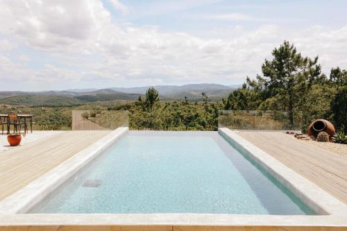 a swimming pool with a view of the mountains at Vale das Estrelas in São Teotónio