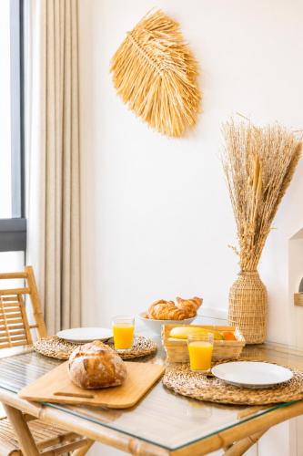 a dining room table with bread and orange juice at Appart'Hôtel & Spa "Les Voiles" Le Houat in Carnac