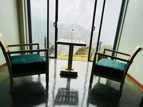 two chairs and a table in front of a large window at ECHO Knuckles Nature Resort in Hunnasgiriya