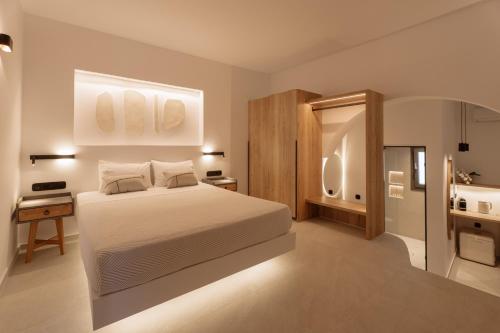 a bedroom with a white bed and a bathroom at Ios Panoramic Sea view stylish suite with pool in Tzamaria