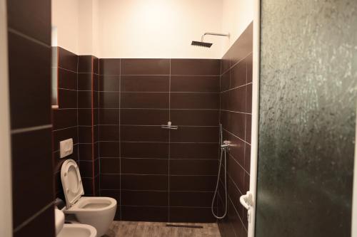 a bathroom with a toilet and a shower with black tiles at Agora Apartments in Dhërmi