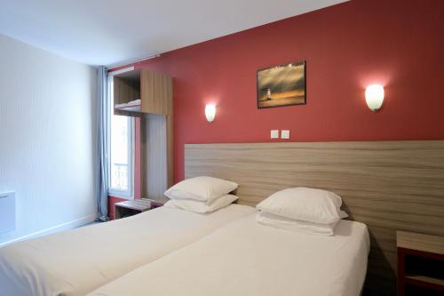 two beds in a room with red walls at Hipotel Paris Gambetta République in Paris