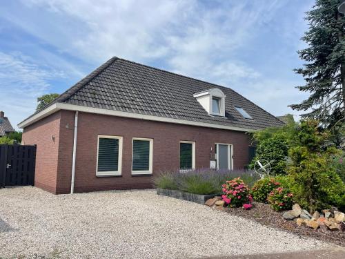 a red brick house with windows and a driveway at Homestay Bij de Heldinnen in Helden