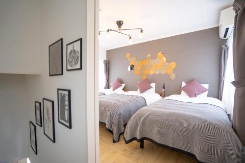 a bedroom with three beds with white and pink pillows at Lino下伊福 in Okayama
