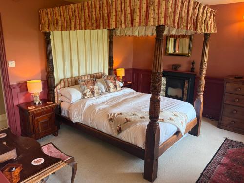 a bedroom with a canopy bed and a fireplace at The Hunters Rest Inn in Clutton