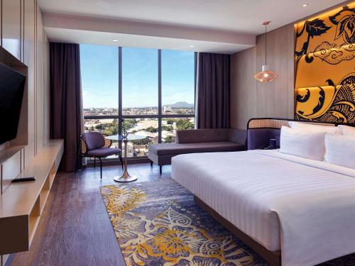 a hotel room with a bed and a television at Grand Mercure Malang Mirama in Malang