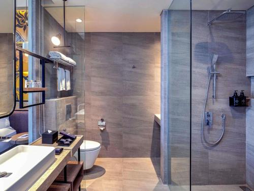 a bathroom with a shower and a toilet and a sink at Grand Mercure Malang Mirama in Malang