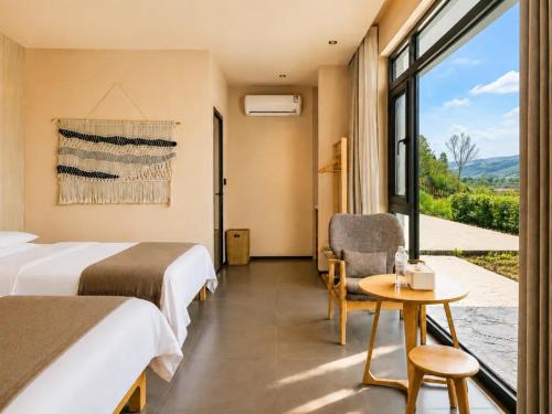 a hotel room with two beds and a table and a window at Houshan Park House in Narat