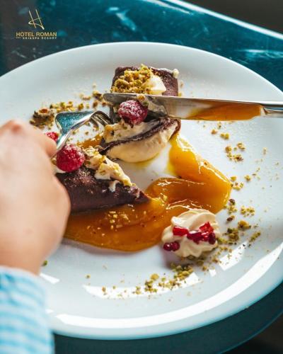 a person is eating a plate of food at Hotel Roman Maramures - Ski & Spa Resort in Statjunea Borsa
