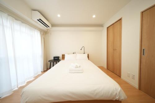 a white bed in a room with a large window at Hotel Otsukahouse in Tokyo