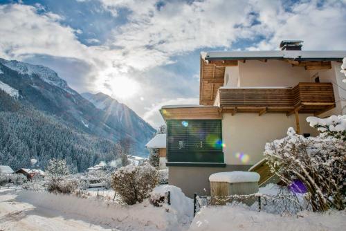 a house covered in snow with mountains in the background at Ferienwohnung Wald in Wald im Pinzgau