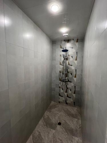a bathroom with a shower with gray tiles at Ohanavan Garden Guesthouse in Oganavan