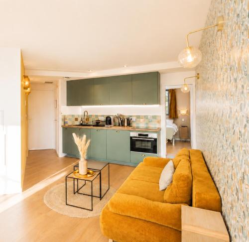 a living room with a couch and a kitchen at Appart'Hôtel & Spa "Les Voiles" Le Brehat in Carnac