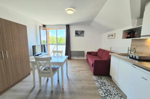 a kitchen and a living room with a red couch at Studio 2 pers avec accès piscine et sauna in Les Déserts